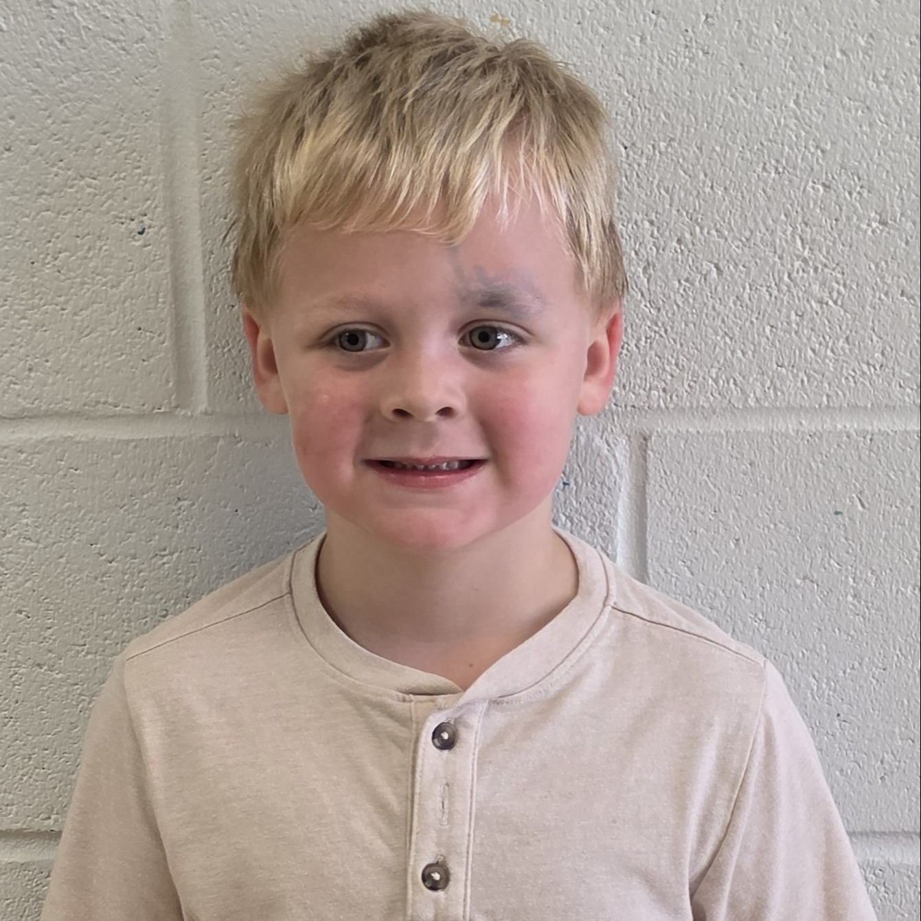 young boy with blonde hair wearing a tan henley