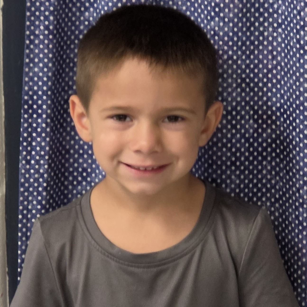 young boy with dark hair wearing a gray t-shirt
