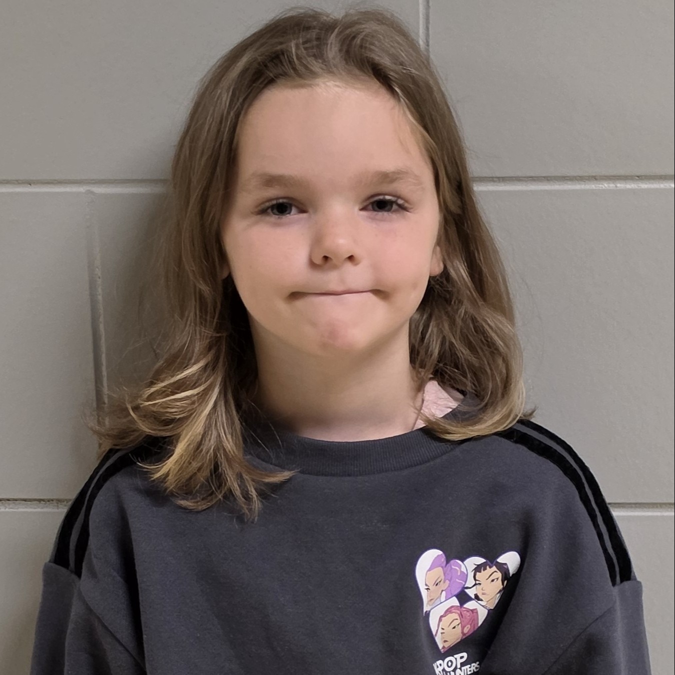 young girl with sandy blonde hair wearing a gray sweatshirt