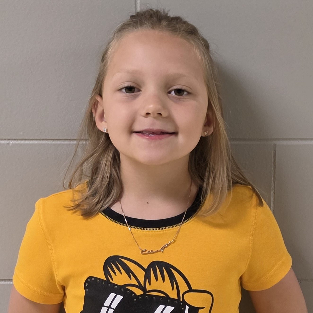 young girl with light brown hair pulled up wearing a yellow Garfield t-shirt