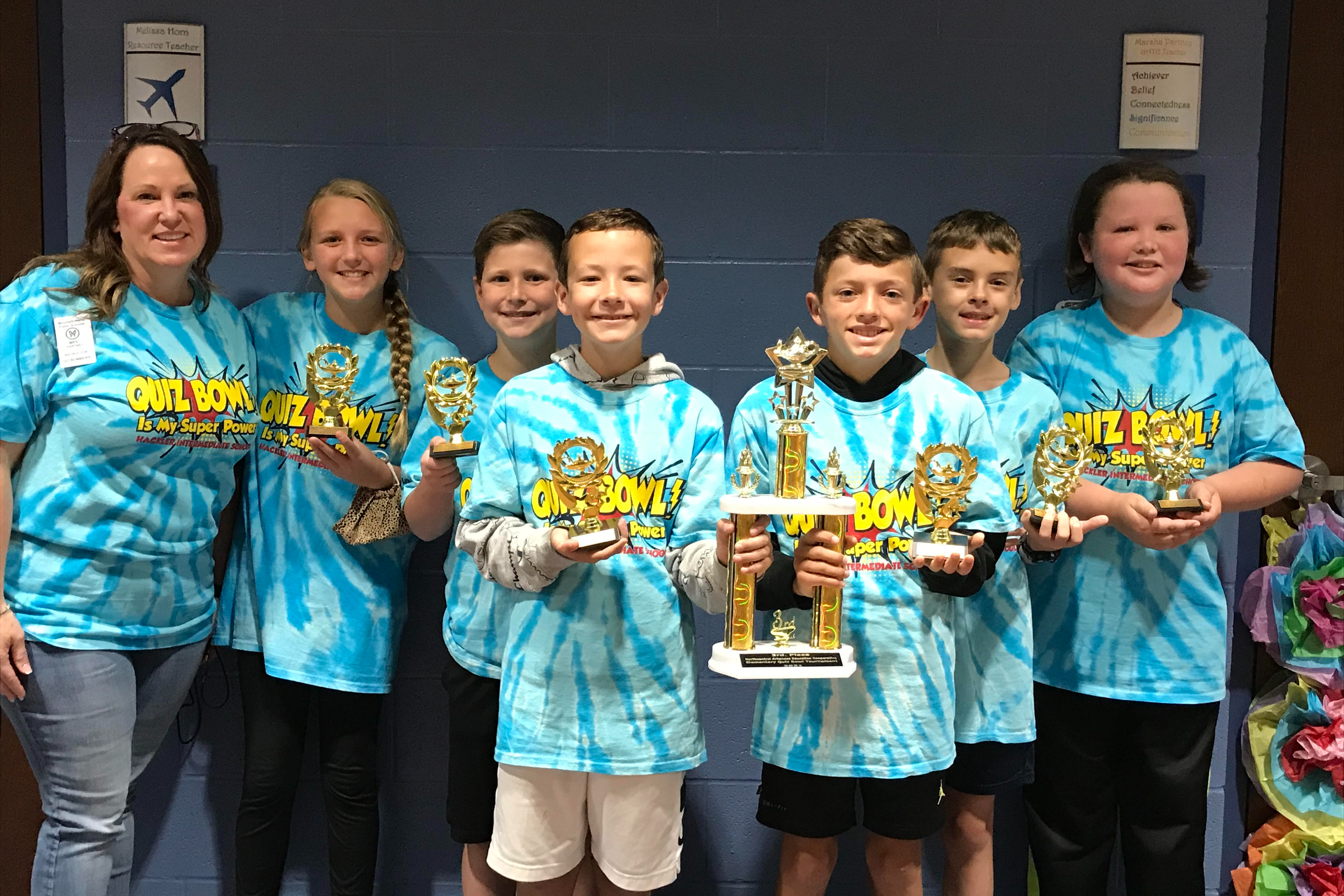 Quiz bowl team from intermediate school holding trophies. 
