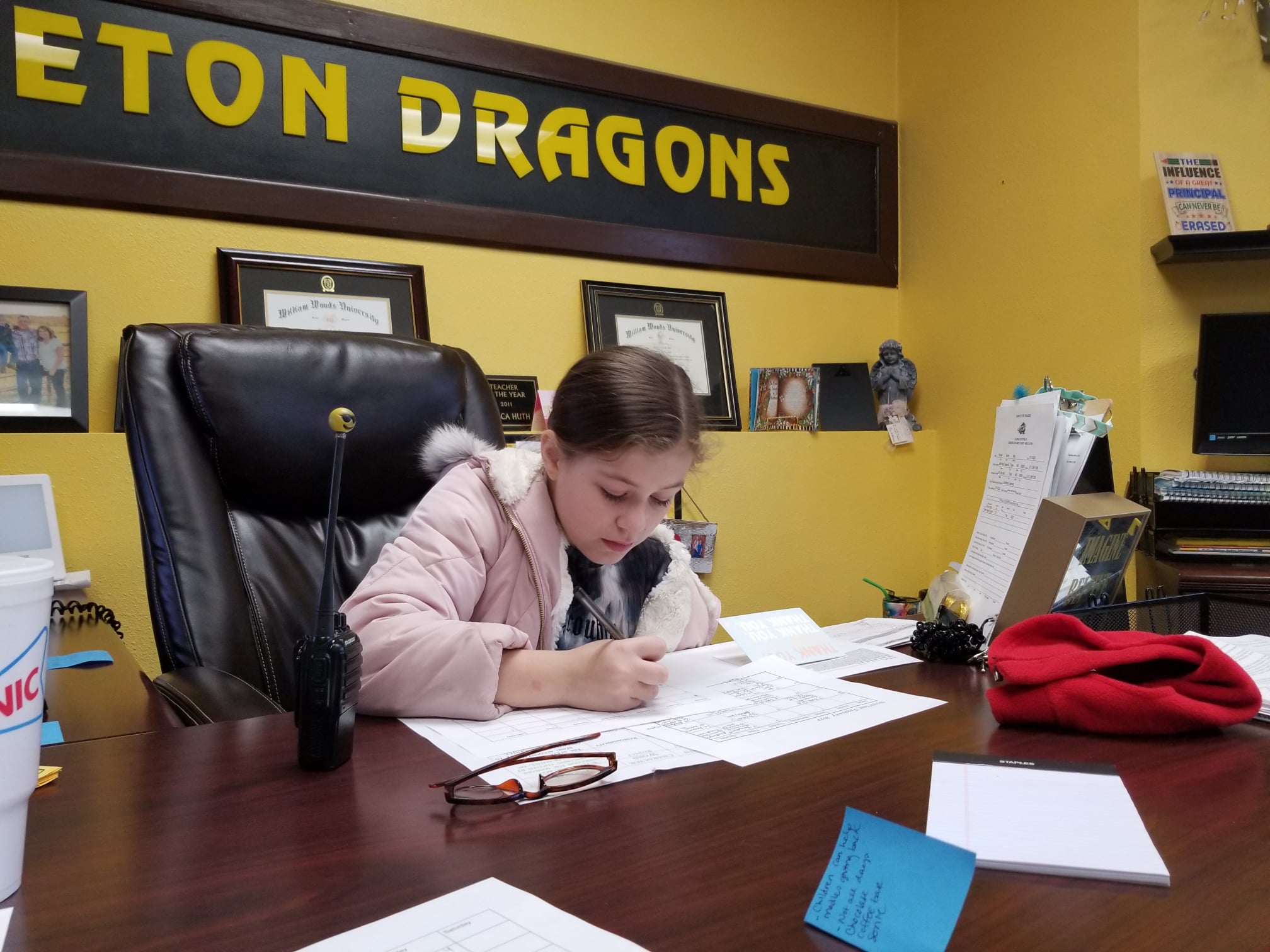students serving as principal for the day sits at elementary principals desk