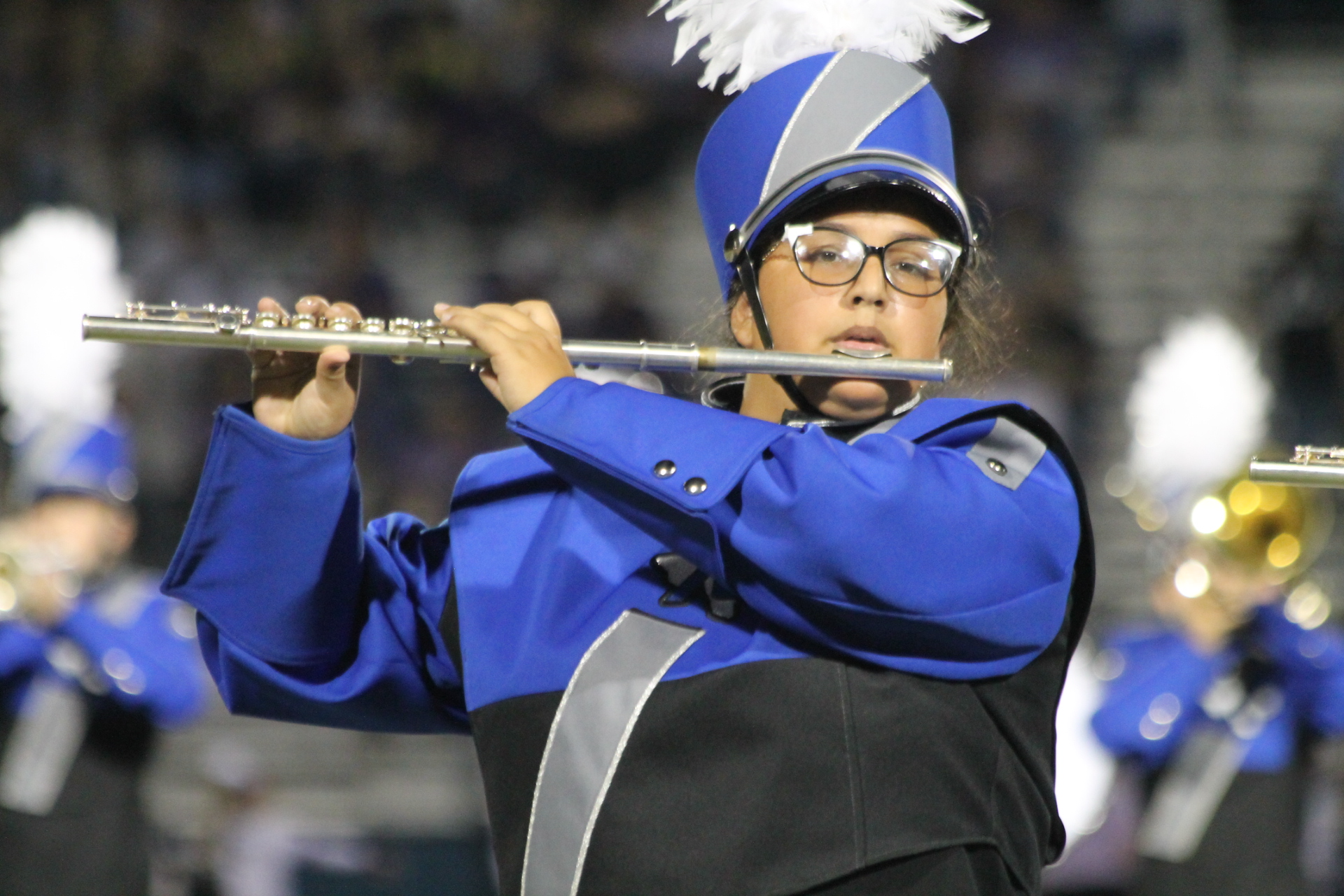 student playing the flute on the field in uniform