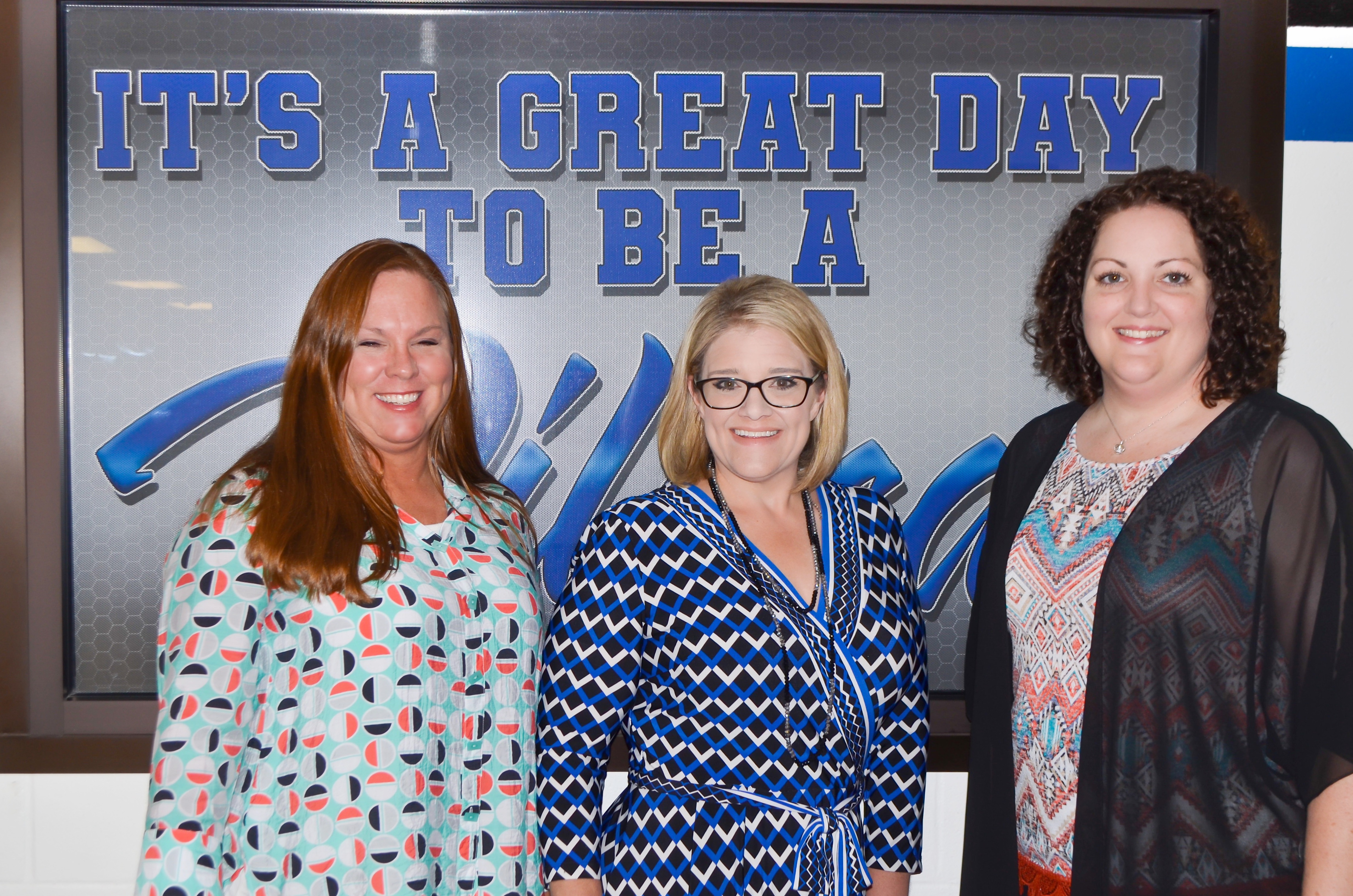 Mrs. Knight, Mrs. Melton, and Mrs. Timmons posing in front of the "it's a great day to be a wildcat" window.