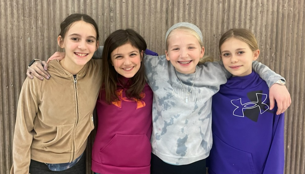 Four girls pose for a picture with their arms around each other