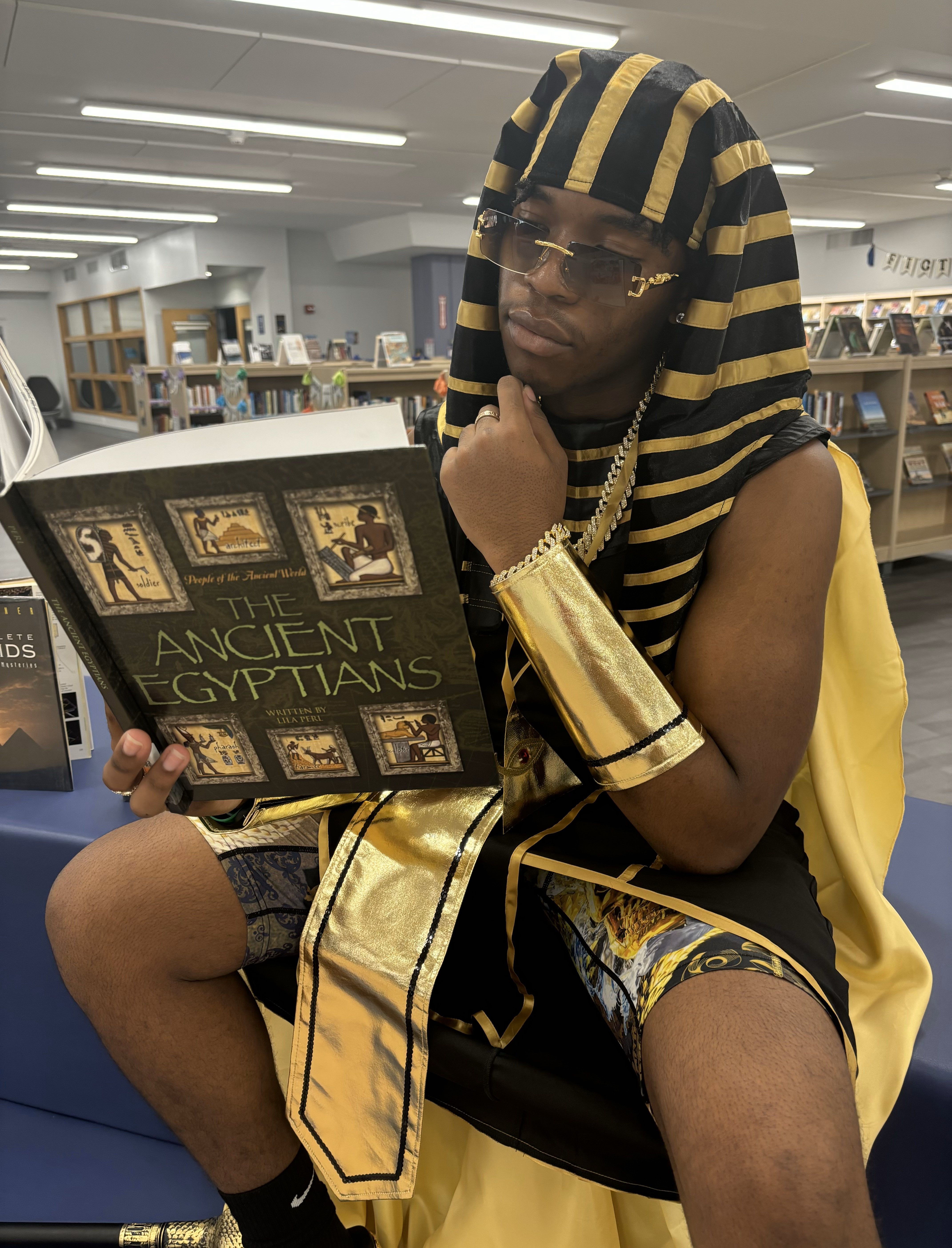 Student dressed in a Pharaoh Halloween Costume reading a book about Ancient Egypt