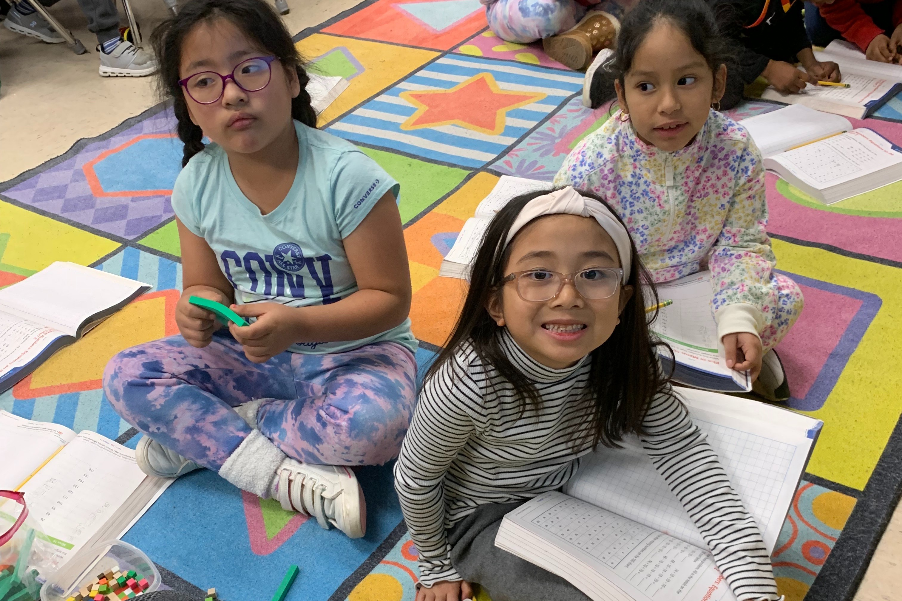 Students holding books and math manipulatives.