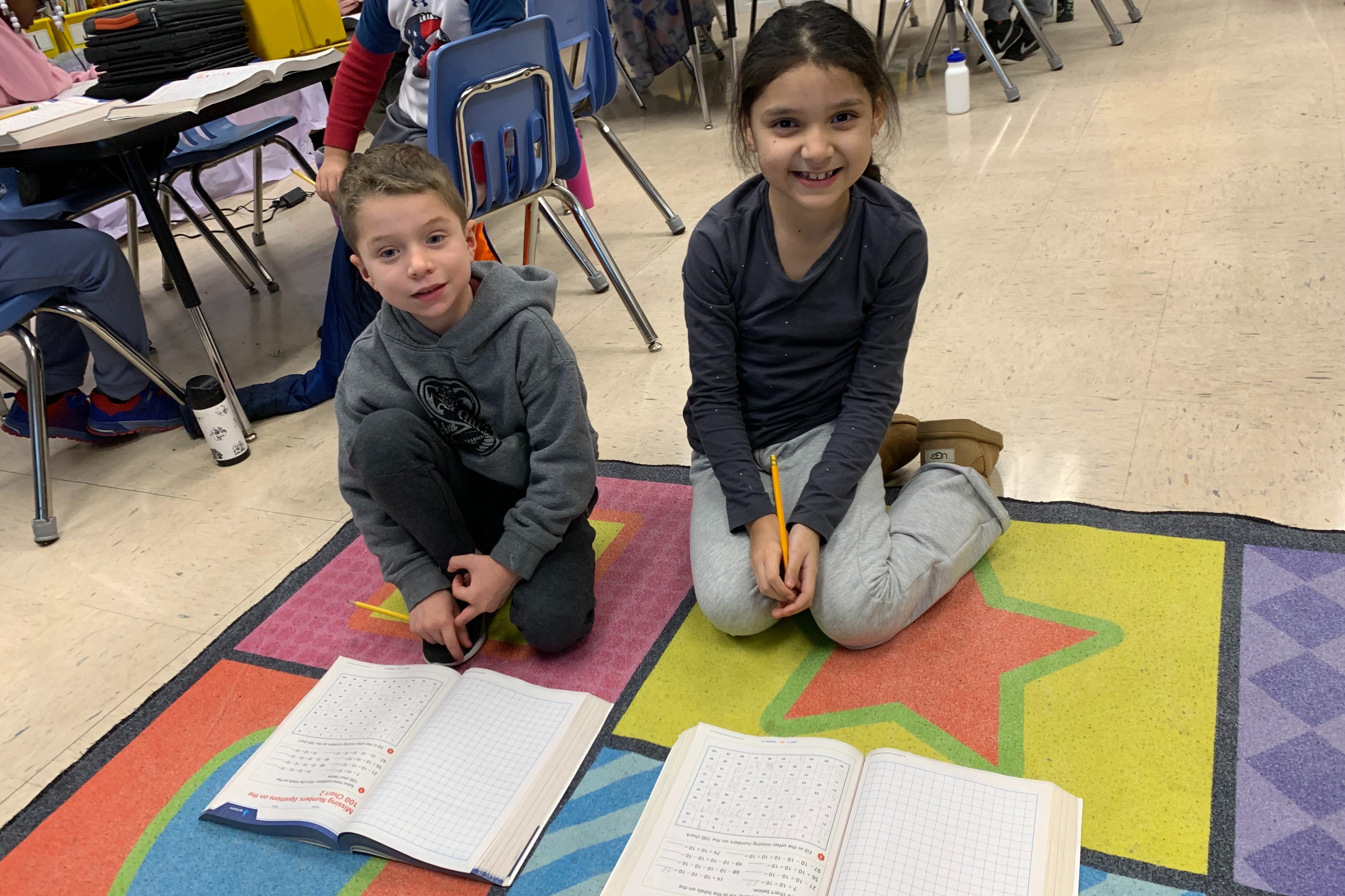 Two students work with Math workbooks.