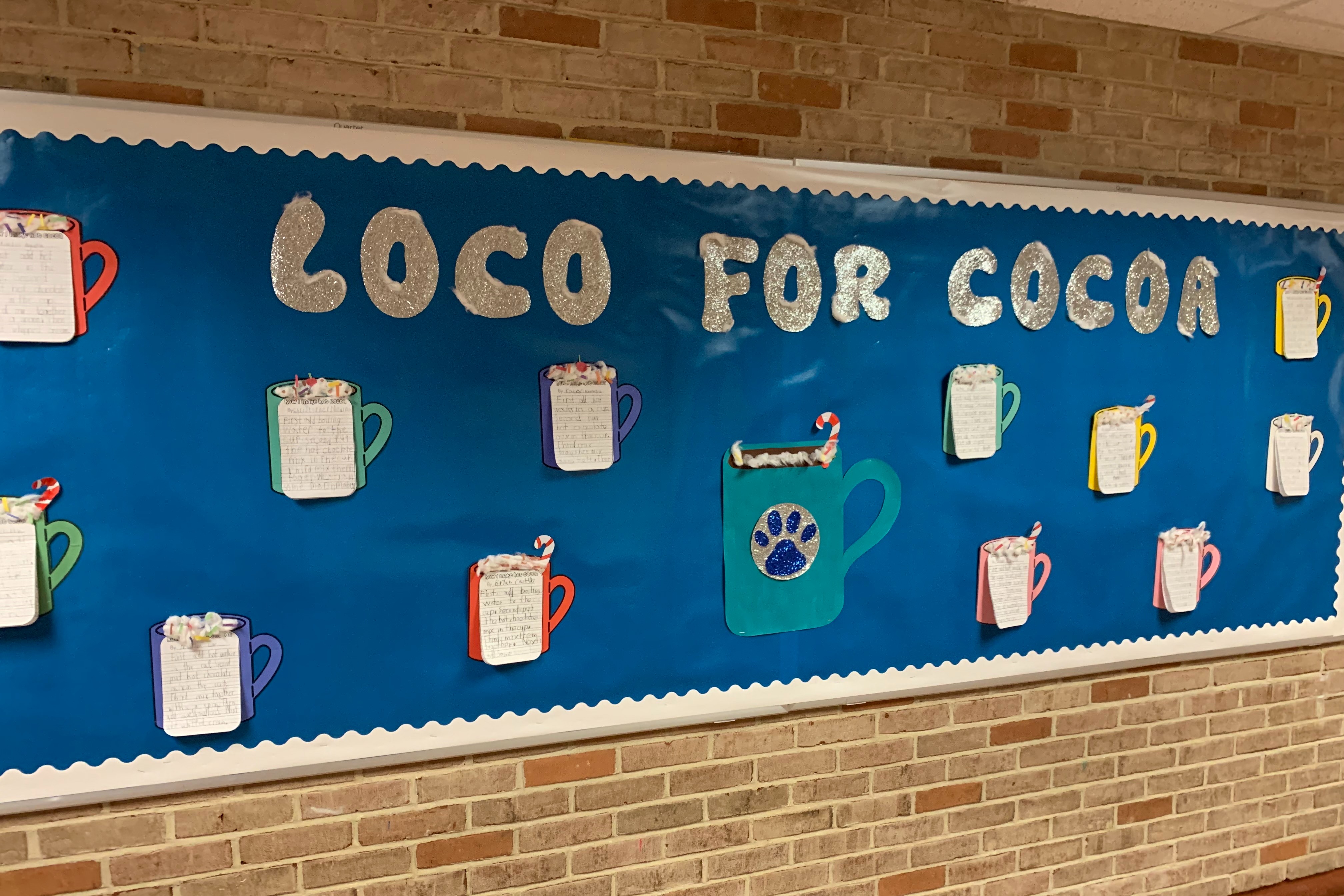 Bulletin board of cups of cocoa with writing on them