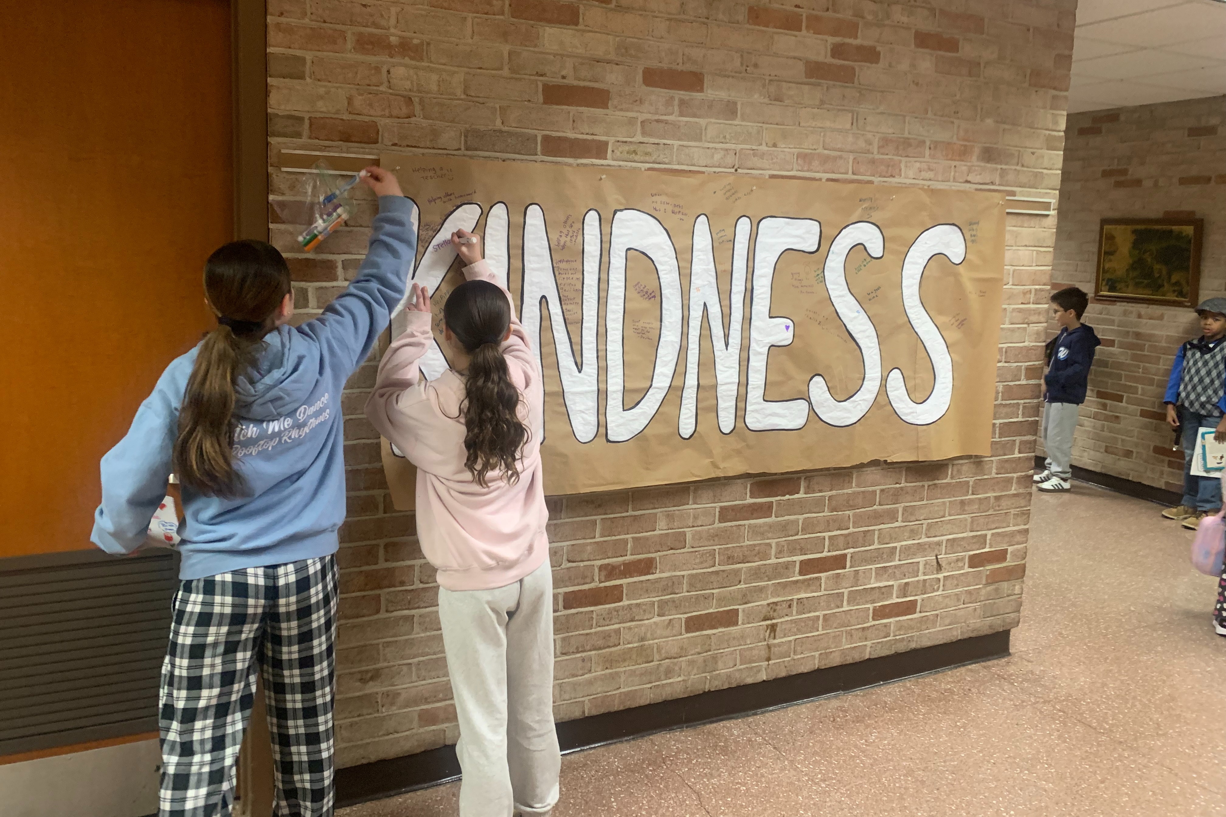 2 students create a Kindness bulletin board.