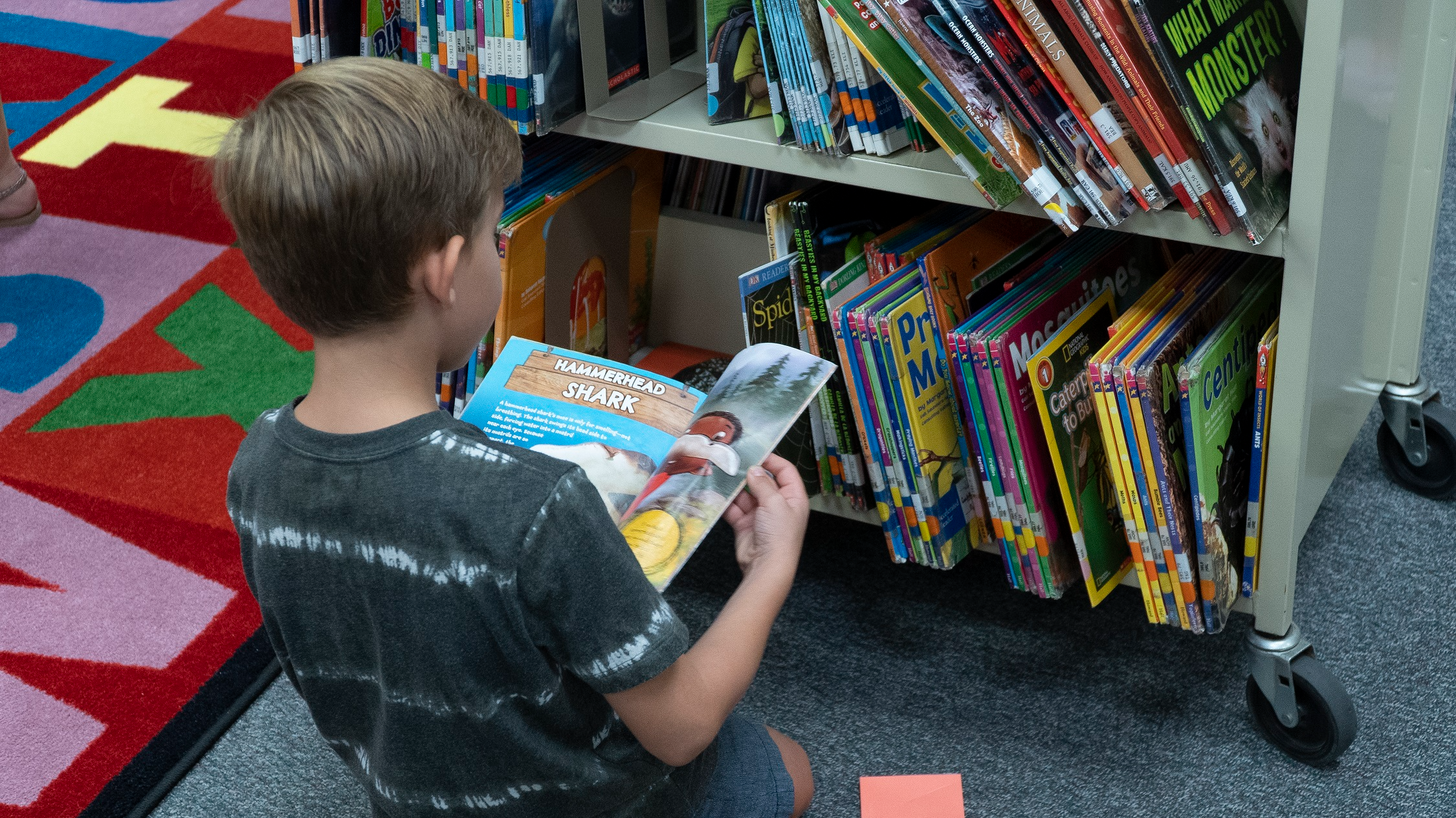 student stting on the floor looking at a cart of books