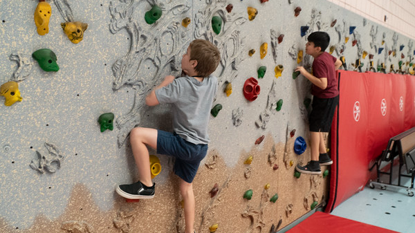 two students climbing on a climbing wall