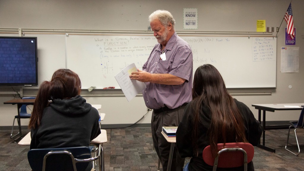 teacher standing in front of two students in a classroom