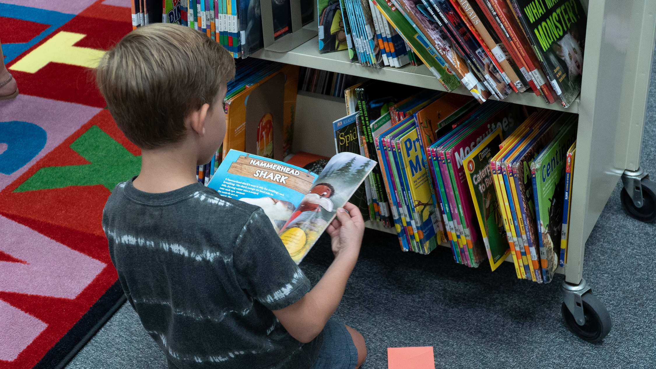 student stting on the floor looking at a cart of books