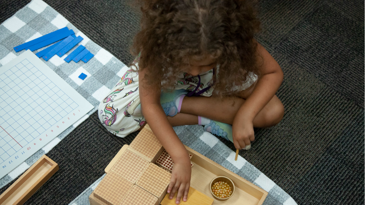 student sitting on floor with manipulative math blocks