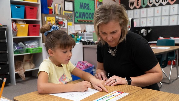 teacher working with student sitting at a desk