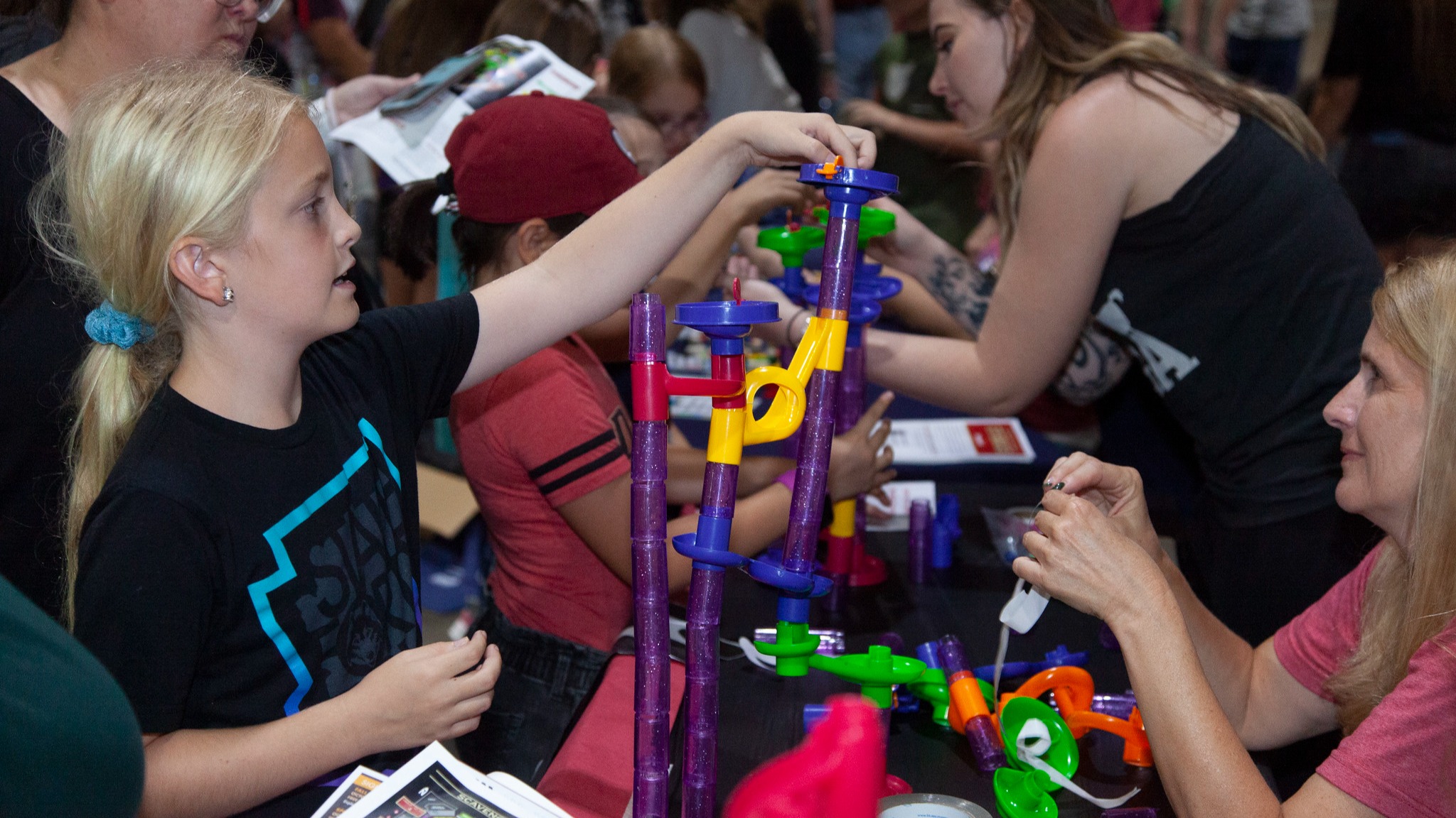 Student working with adults to build something with connecting blocks
