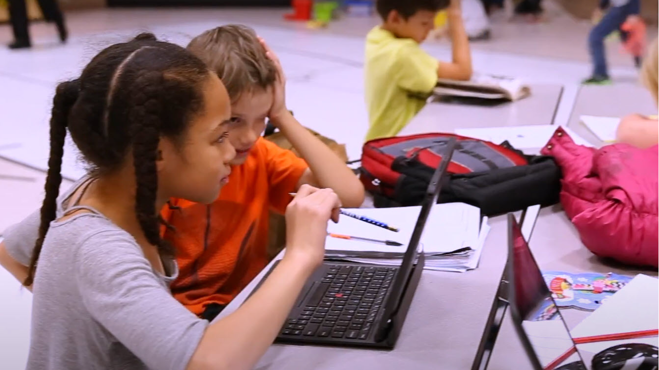 two students looking at a laptop screen