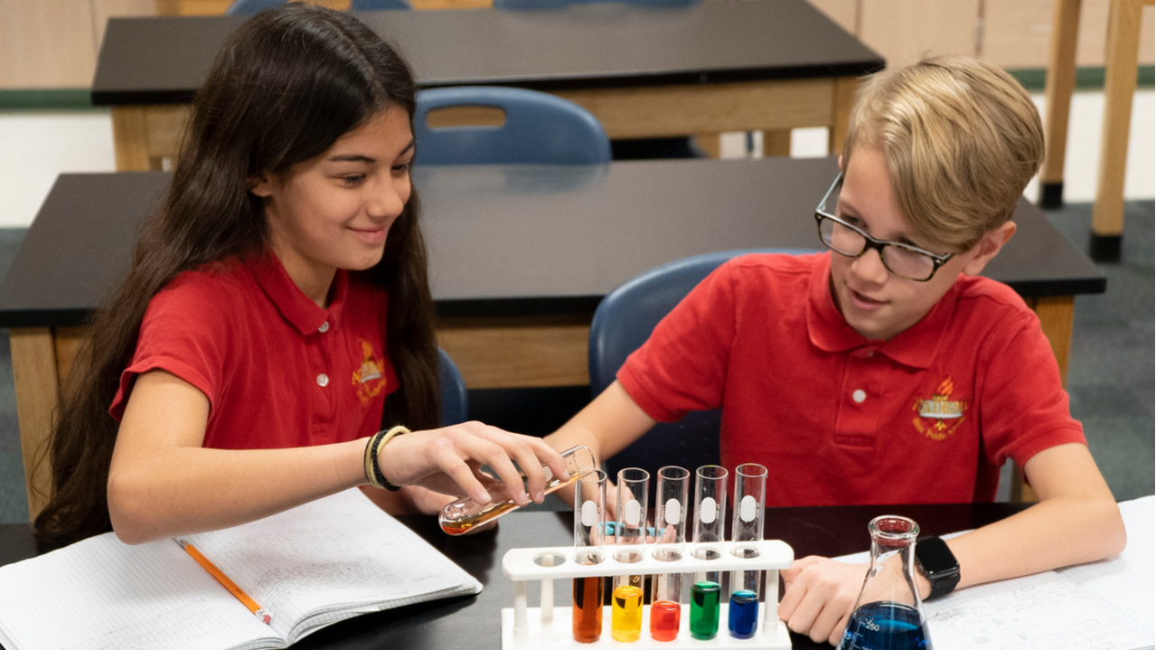 two students pouring something in a beaker