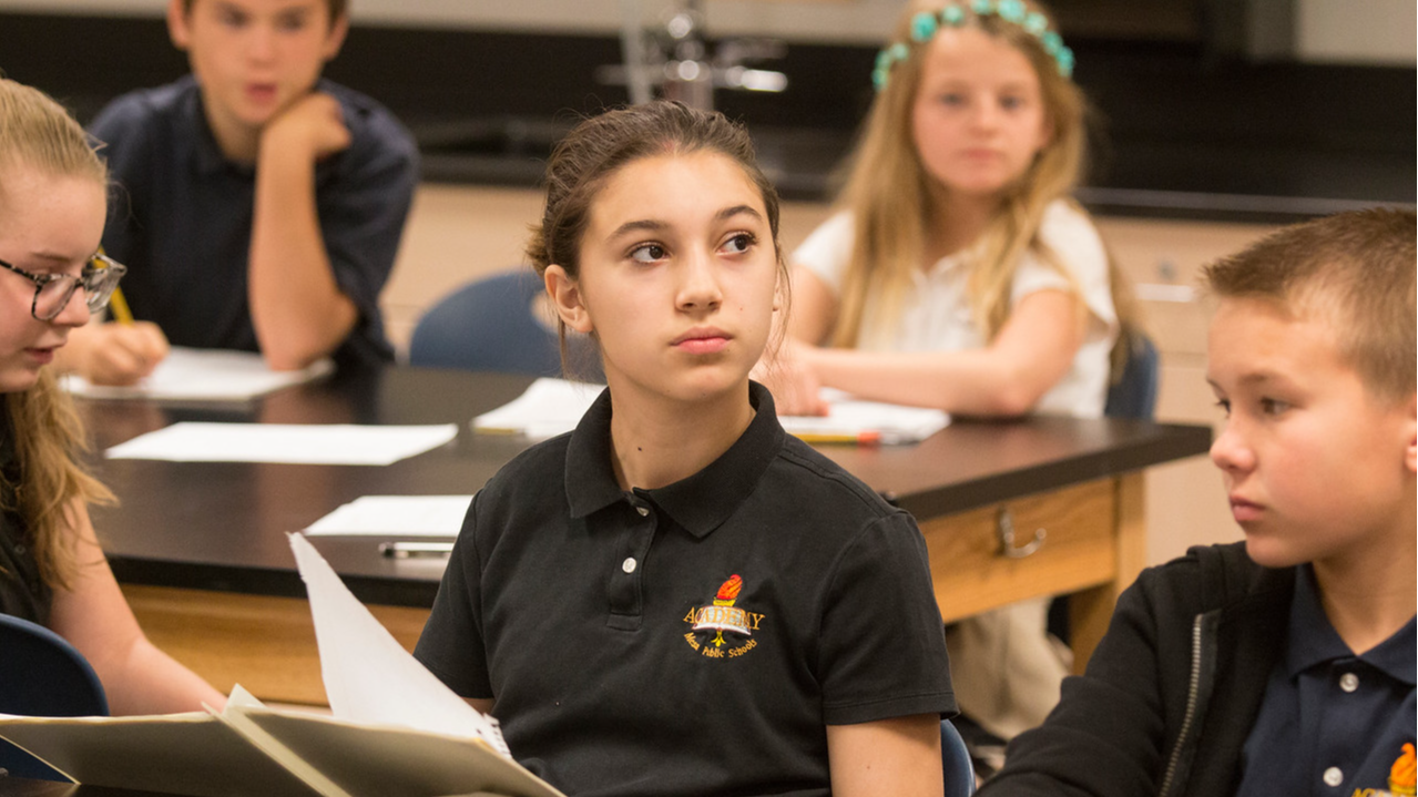 students sitting in classroom with notebook in front of them