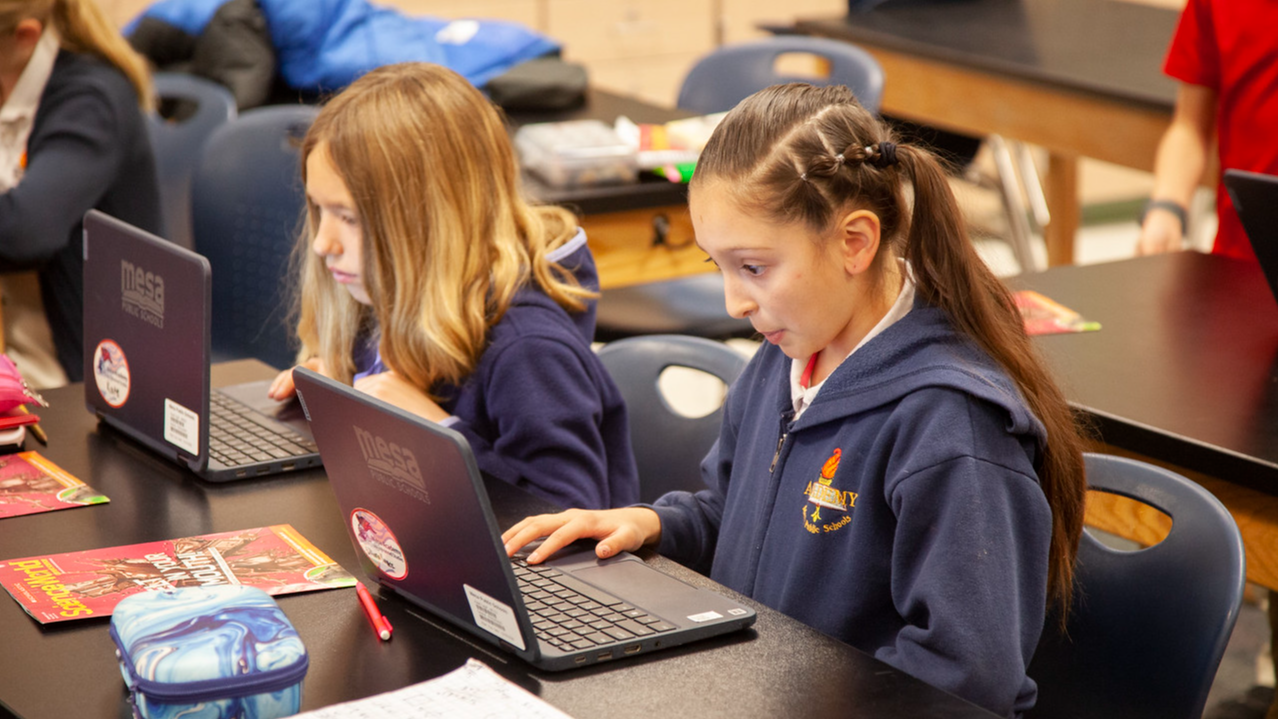 two students working on laptopes