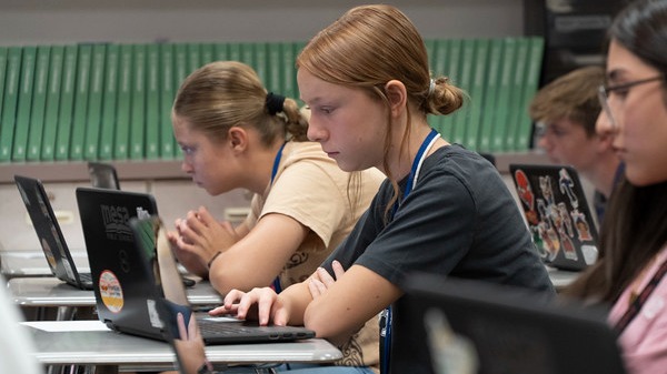 three students working on laptop computers