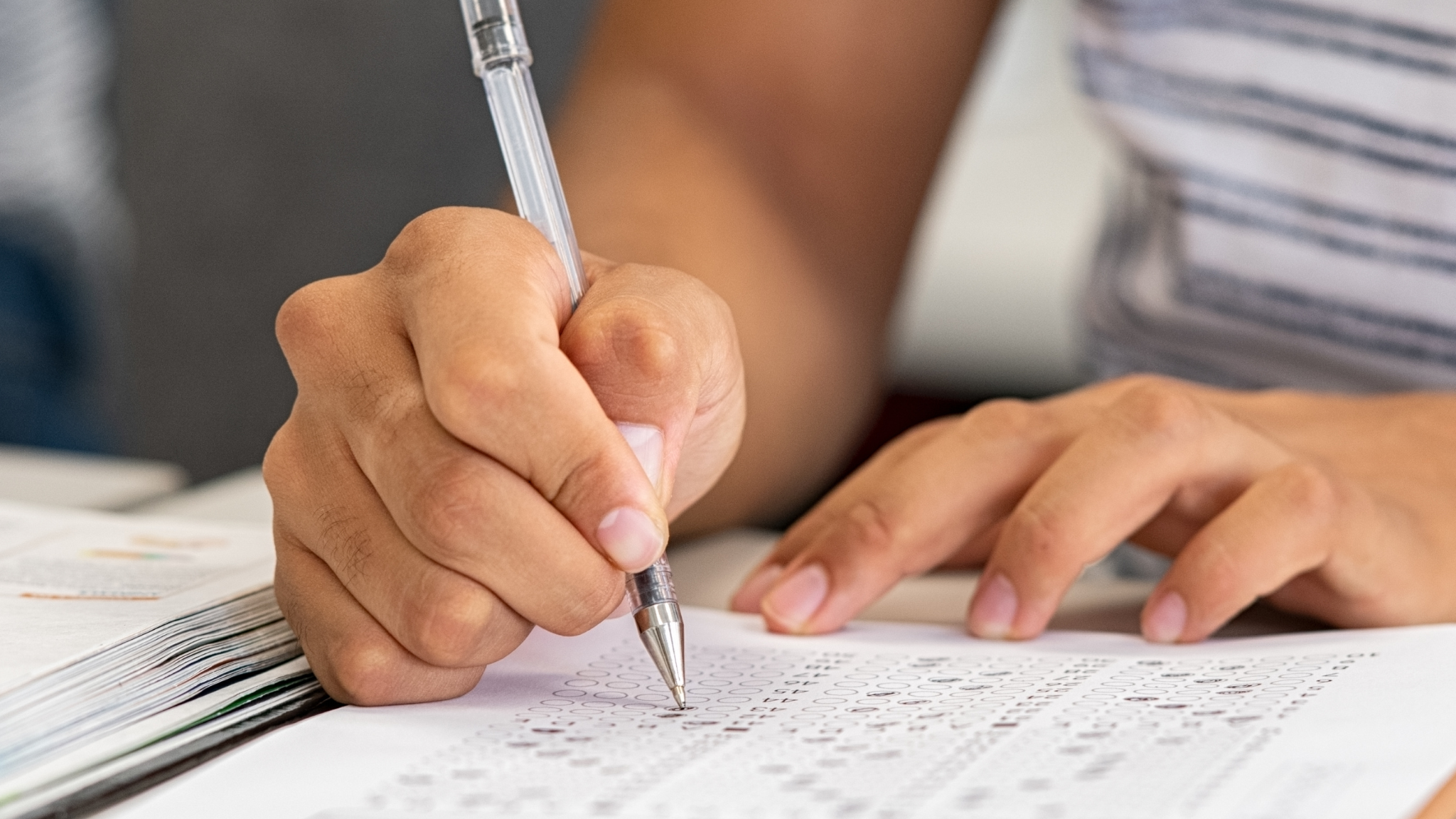 student hands writing on paper with a pen