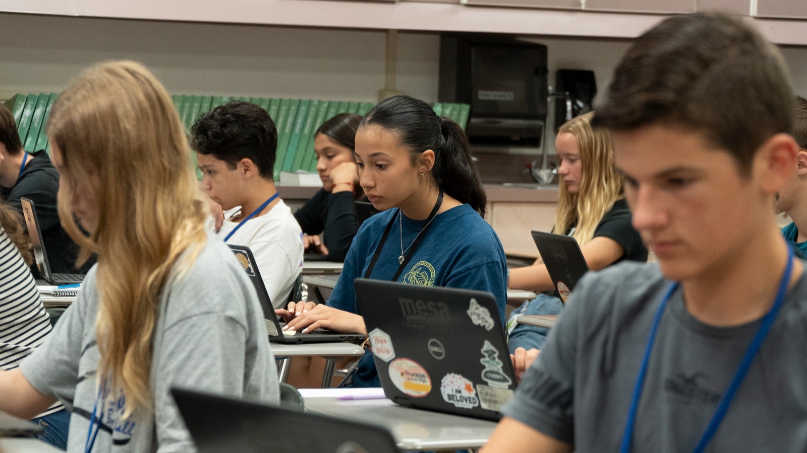 students sitting at desks working on laptops