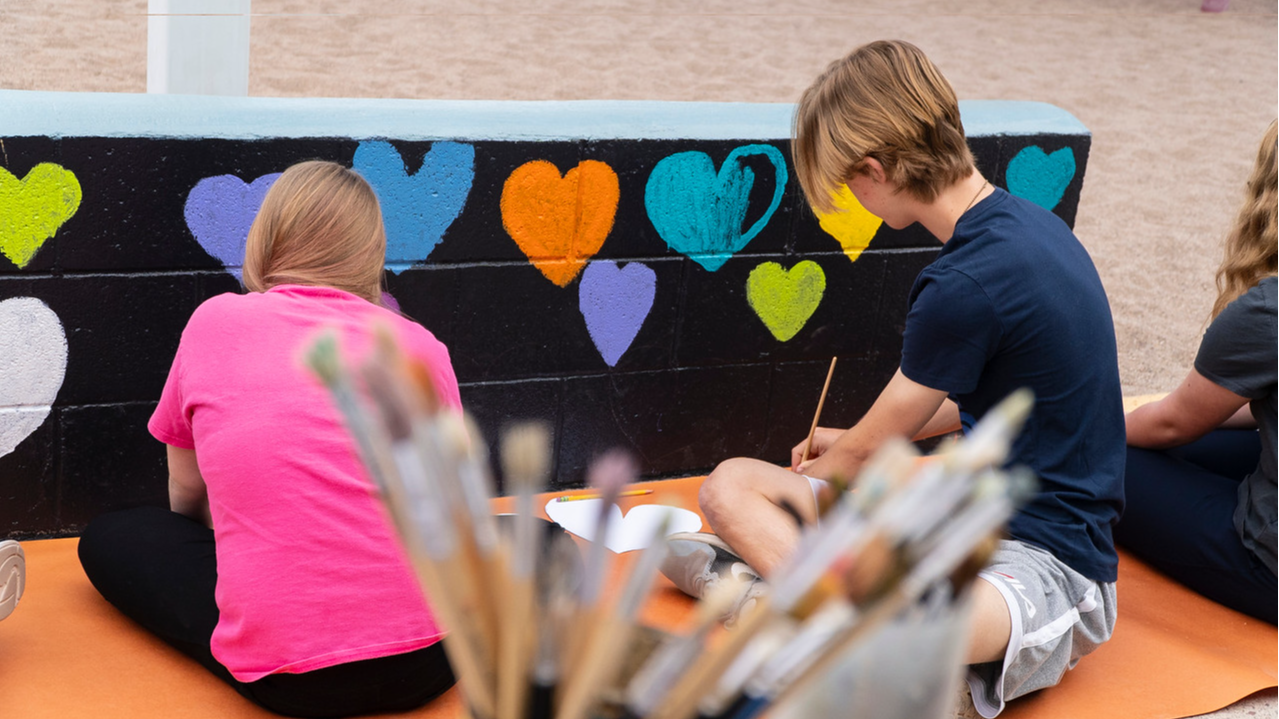 two students painting on wall