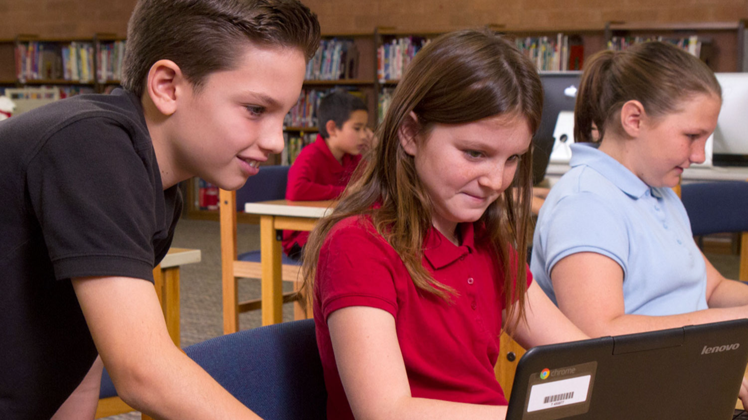 3 students in library working on laptops