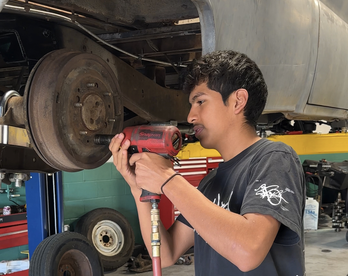 Student working on a car wheel in an auto shop