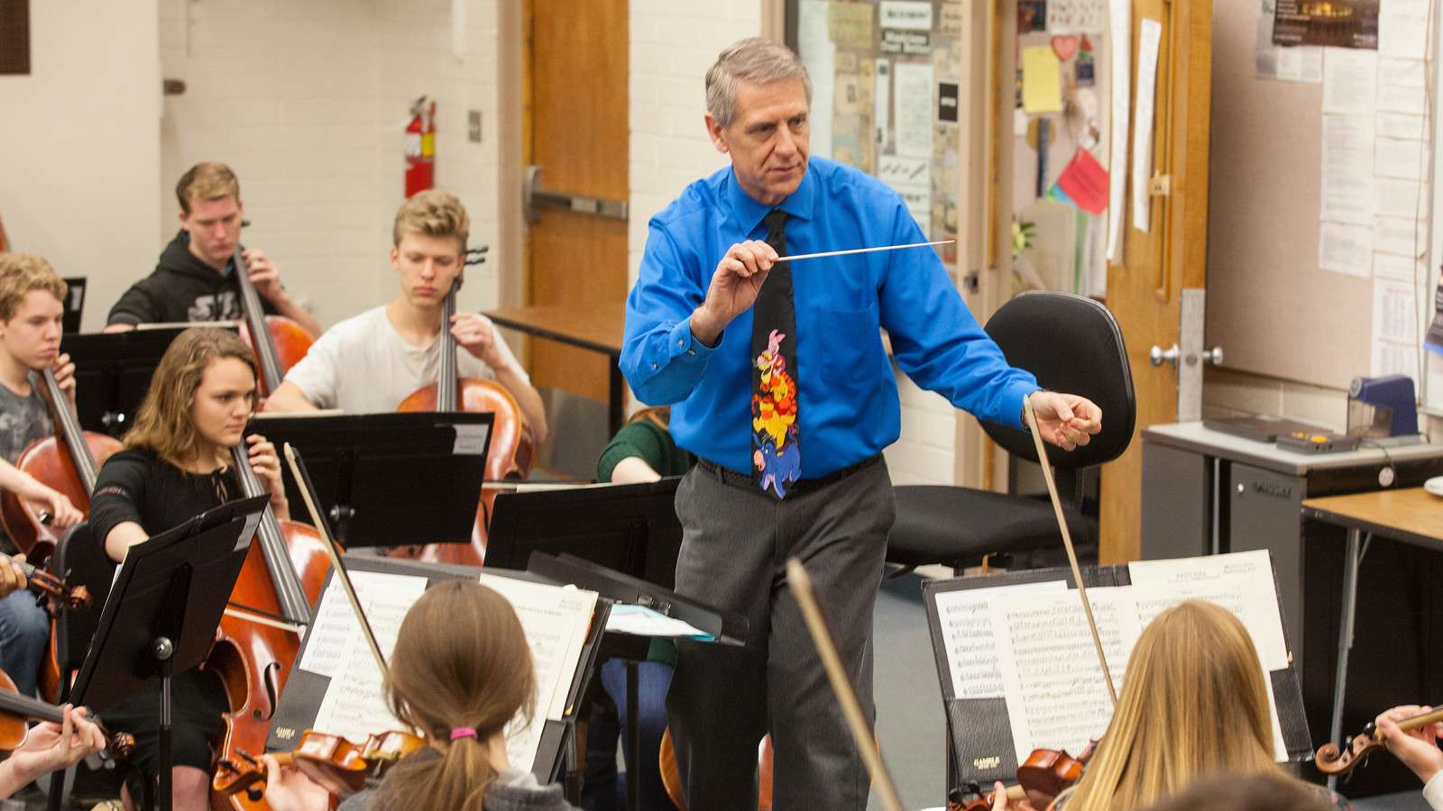 music teacher leading student orchestra