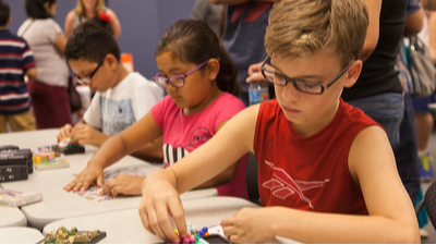 three elementary students working  puzzles