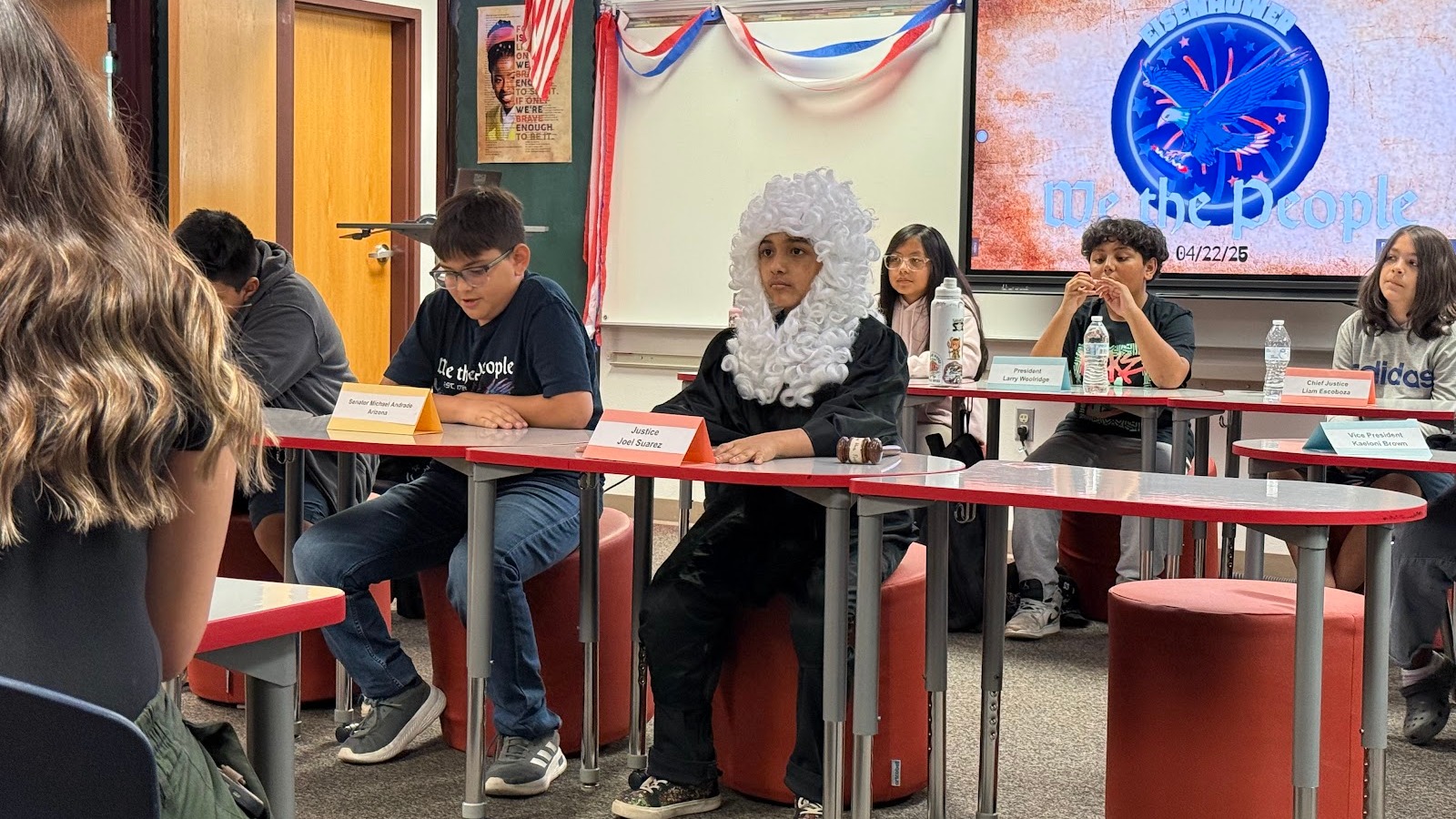 students sitting in a classroom participating in a club meeting