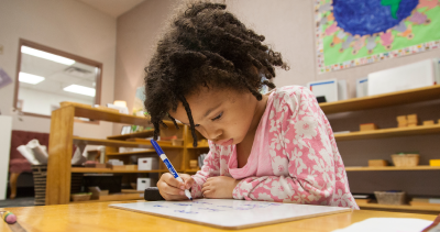 child writing on tablet at a desk