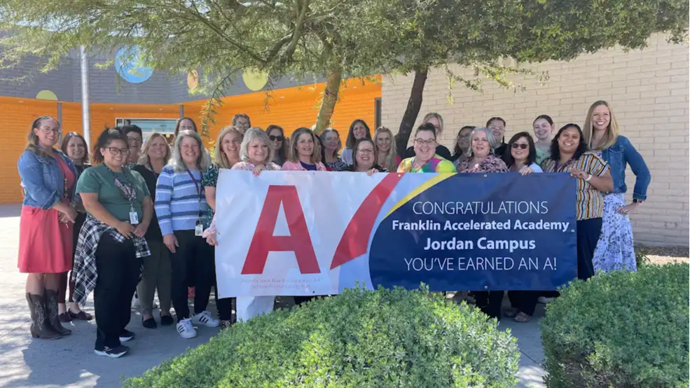 Staff holding banner that says Congratulations Franklin Accelerated Academy Jordan Canpus You've earned an A