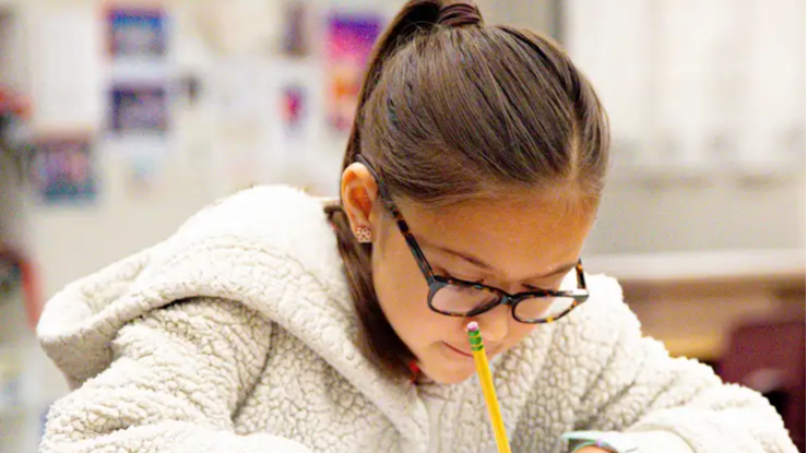 student writing in a notebook with a pencil