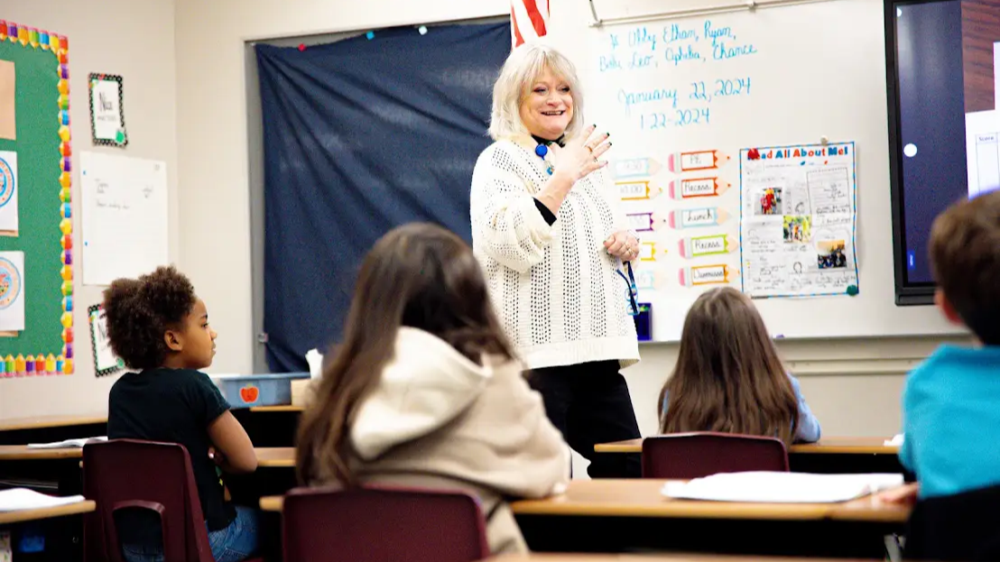 teacher standing at white board in front of 4 students