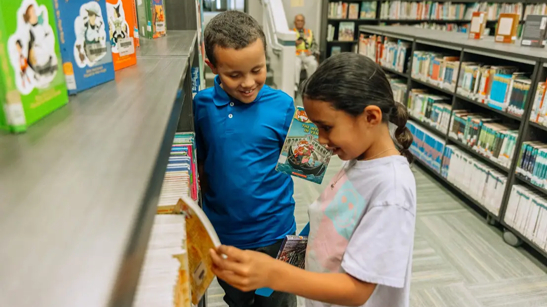 two students picking out books in a library