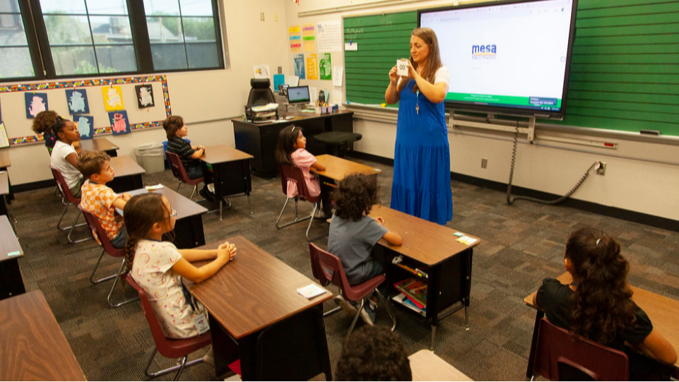 teacher standing in front of class showing flashcards