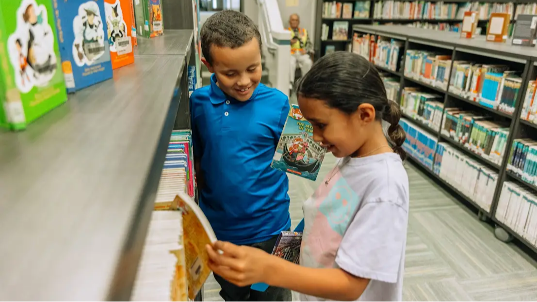 two students looking at books in a library