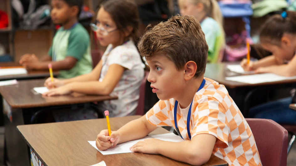 Students sitting at desks writing with pencils on paper