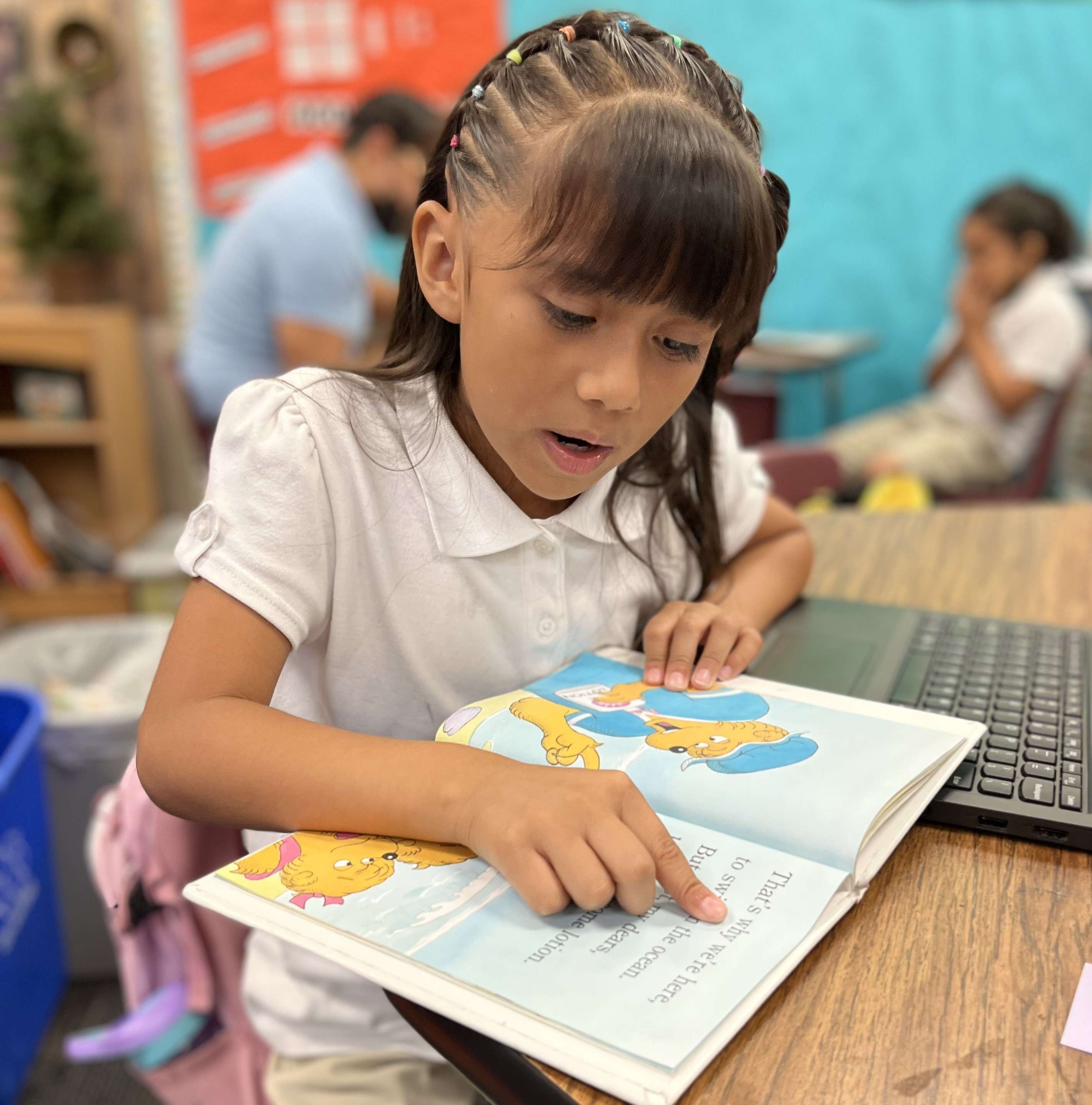 student pointing to words in a book while reading