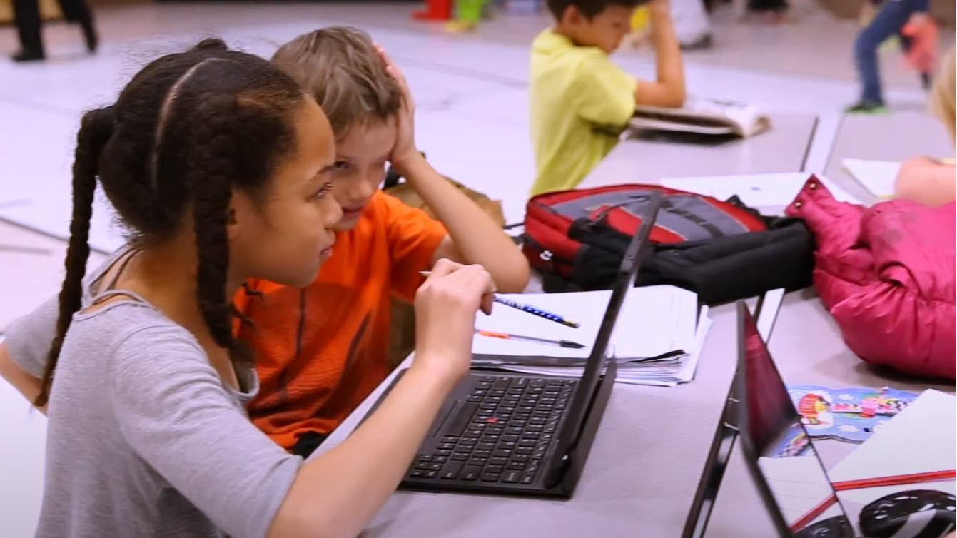 two students looking at a laptop screen