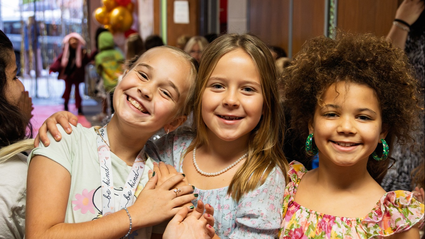 three students standing in a hallway next to each other ans smiling