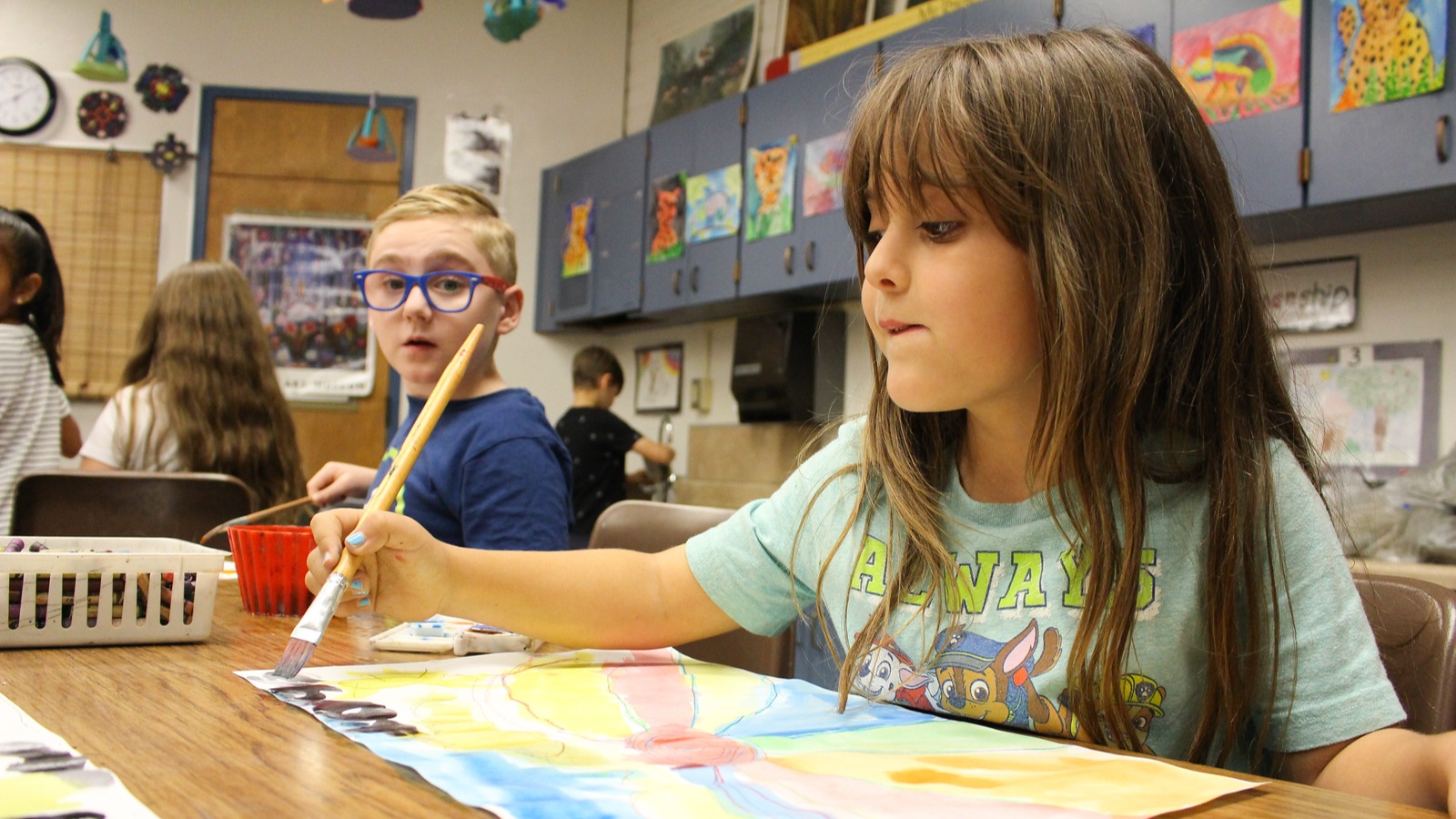 students sitting at tables painting