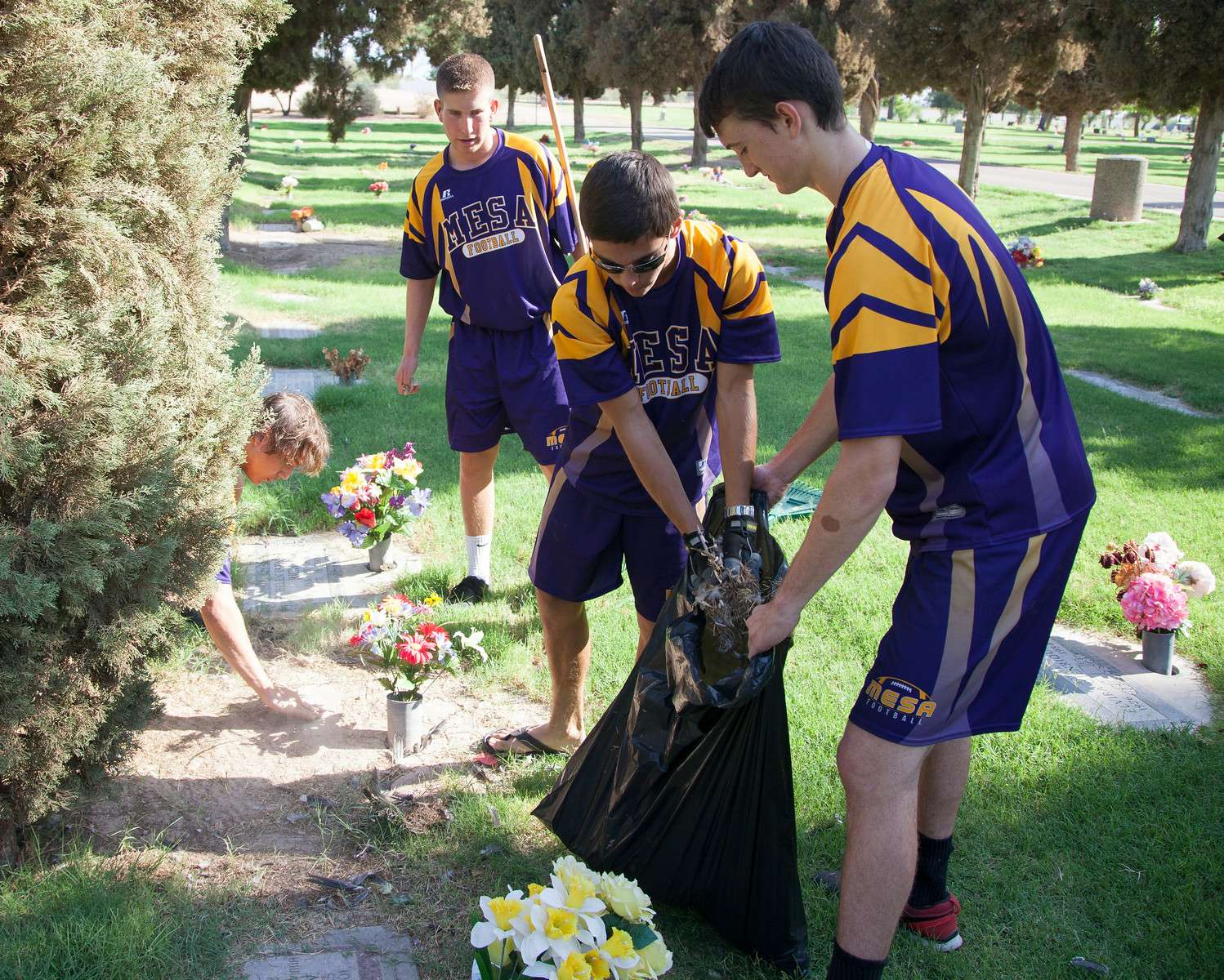Football players cleaning cemetary
