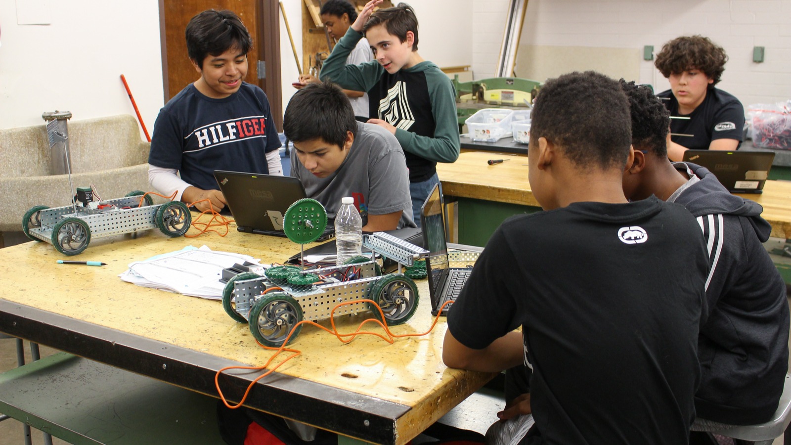 five stludents standing around a table working on an electric model car