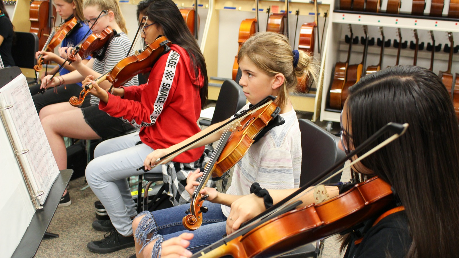 three students playing the violin