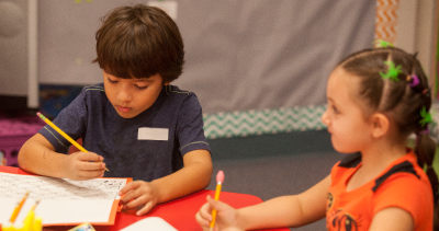 two students writing in a notebook